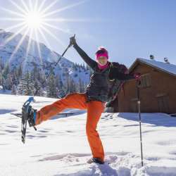 randonnées en raquettes à Malbun sous le soleil Une joyeuse randonneuse en raquettes profite de l'hiver à Malbun, au Liechtenstein, sous un soleil radieux.