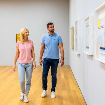Un couple se promène dans le musée d'art du Liechtenstein à Vaduz et regarde des œuvres d'art contemporaines accrochées au mur.