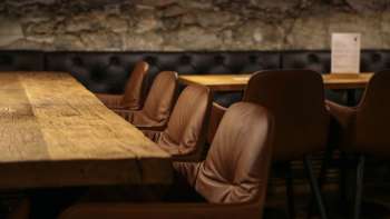 Détail d'une table en bois avec de confortables chaises en cuir dans l'agréable coin salon du WY Weinbar.