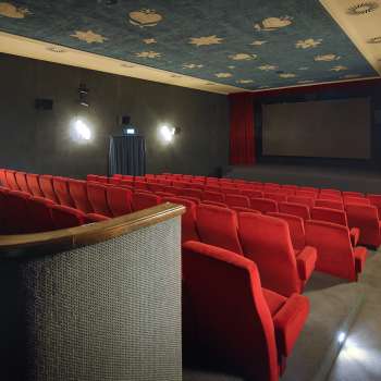 Vue latérale de la salle de cinéma de l'Altes Kino Vaduz avec des fauteuils rouges et un éclairage d'ambiance.