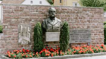 Monument Rheinberger à Vaduz sous lequel se trouvent des fleurs rouges