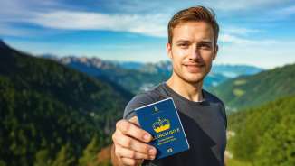 L'homme montre le Passeport découvertes ALL INCLUSIVE avec un panorama de montagnes en arrière-plan