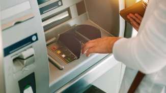 Femme saisissant son code PIN sur un distributeur automatique de billets générique, un portefeuille à la main