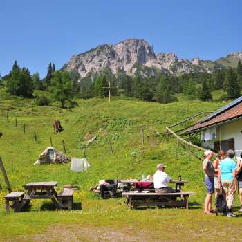 Vue sur les montagnes depuis l'alpage de Guschg, où plusieurs personnes font une pause et profitent de la vue.