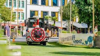Le train multicolore de Städtle traverse le terrain de fête du Summerträff à Vaduz, entouré de visiteurs et d'une atmosphère estivale.