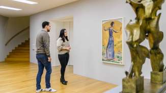 Un couple regarde des peintures dans la galerie lumineuse du Kunstmuseum Liechtenstein avec une sculpture moderne au premier plan.