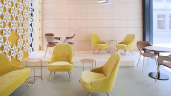 Café moderne avec des fauteuils jaunes élégants, un décor minimaliste et des fenêtres lumineuses