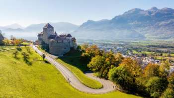 Château de Vaduz sur une colline avec vue sur la vallée du Rhin et les montagnes environnantes.
