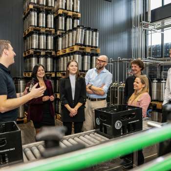 Groupe de visiteurs lors d'une visite guidée de l'entrepôt de fûts de la brasserie avec les explications d'un collaborateur de la brasserie.
