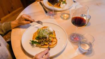 Gros plan sur un plat principal servi avec style et accompagné de vin rouge au Gasthof Au.