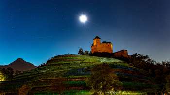 Le château illuminé de Gutenberg la nuit sous la pleine lune, niché dans les vignobles