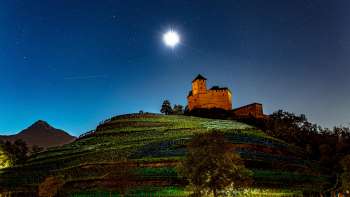 Le château de Gutenberg la nuit, sous la pleine lune, niché au milieu des vignes