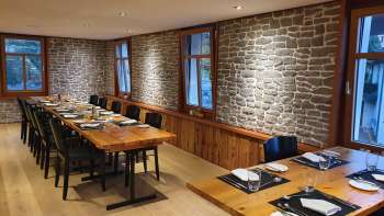 Salle de restaurant élégante avec de longues tables en bois, des murs en pierre et une décoration moderne