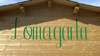 Vue sur le logo vert de Lömagarta, qui s'affiche avec style sur la façade en bois de l'agréable Biergarten.