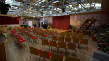 Grande salle de réunion de la Kreativ Akademie, inondée de lumière, avec scène, rideaux rouges et rangées de chaises - idéale pour les séminaires, les conférences et les événements créatifs au Liechtenstein. Grande salle de réunion de la Kreativ Akademie, inondée de lumière, avec scène, rideaux rouges et rangées de chaises - idéale pour les séminaires, les conférences et les événements créatifs au Liechtenstein.