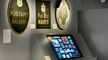 Salle du musée avec d'anciennes plaques postales et un affichage numérique sur l'histoire de la poste au Liechtenstein.