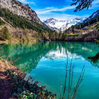 Lac de montagne cristallin lac Gänglesee à Steg, Liechtenstein - encadré de forêts, de montagnes et d'un vert printanier frais