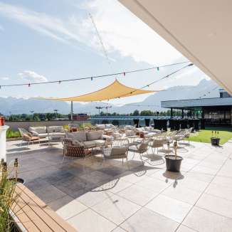 Vaste terrasse avec meubles de salon et voile d'ombrage à l'hôtel kommod à Ruggell - endroit parfait pour se détendre avec vue sur les montagnes.