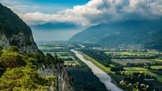 Vue depuis l'Ellhorn à Balzers sur le Rhin et la vallée du Rhin avec ses pentes rocheuses, le cours du fleuve et une large vue sur la région alpine.