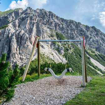Balançoire suspendue sur le Sentier des balançoires Malbun avec vue sur les falaises abruptes et le paysage alpin au Liechtenstein