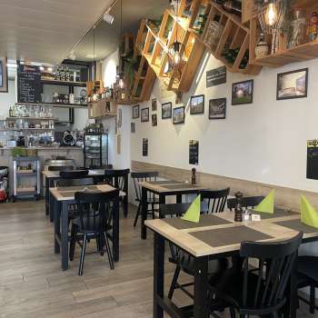 Intérieur de restaurant confortable avec des tables en bois modernes, des serviettes vertes et des éléments décoratifs