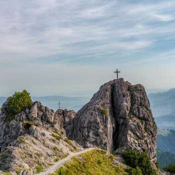 les Trois Sœurs avec deux croix au sommet et une vue étendue sur la vallée et les montagnes environnantes