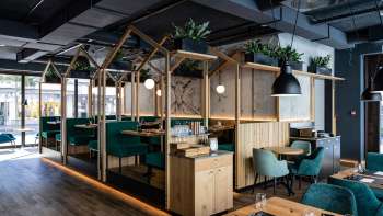 Restaurant moderne avec une construction en bois élégante, des sièges rembourrés verts et une répartition créative de l'espace