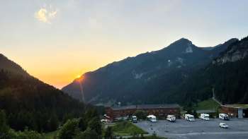 Plusieurs camping-cars sont garés sur l'aire de stationnement de Malbun, avec un panorama montagneux en arrière-plan