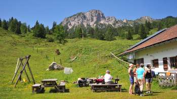 Vue sur les montagnes depuis l'alpage de Guschg, où plusieurs personnes font une pause et profitent de la vue.
