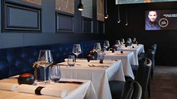 Intérieur élégant de l'Esquire Bar & Bistro à Vaduz avec des tables dressées avec style, une banquette bleu foncé et un éclairage d'ambiance. Intérieur élégant de l'Esquire Bar & Bistro à Vaduz avec des tables dressées avec style, une banquette bleu foncé et un éclairage d'ambiance.