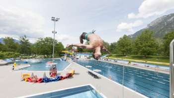 unge saute en salto du plongeoir d'un mètre dans le bassin de la piscine de Mühleholz - la joie estivale à l'état pur.