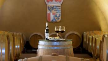 Dégustation de vin d'ambiance dans la cave à vin du domaine princier avec deux verres et une bouteille de vin rouge sur un tonneau en bois.