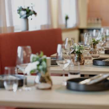 Gros plan sur des tables dressées avec style dans le restaurant RUUF, avec de la vaisselle sombre et des vases de fleurs