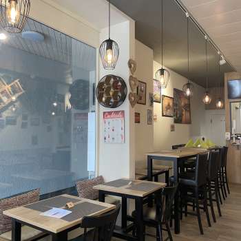 Salle de restaurant aménagée avec style, avec des meubles en bois noir, des sols en bois et des décorations murales créatives