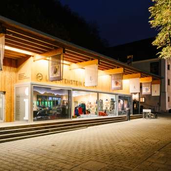Centre d'accueil moderne avec façade en verre à Vaduz la nuit, éclairé de manière accueillante.