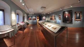 Salle d'exposition du musée national du Liechtenstein avec des portraits historiques et des objets exposés