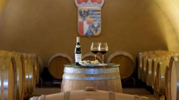 Dégustation de vin d'ambiance dans la cave à vin du domaine princier avec deux verres et une bouteille de vin rouge sur un tonneau en bois.