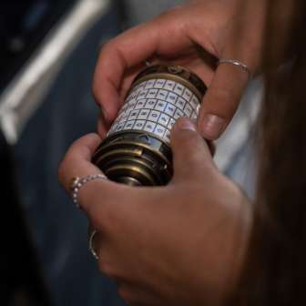 Gros plan sur des mains munies d'une mystérieuse serrure à combinaison dans l'Escape Room Malbun