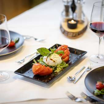 Salade fraîche de tomates et mozzarella avec vin rouge sur une table dressée au JUFA Hotel Malbun