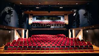 Vue depuis la scène sur les rangées de sièges rouges et la technique d'éclairage dans la salle de spectacle moderne du TAK Theater Liechtenstein