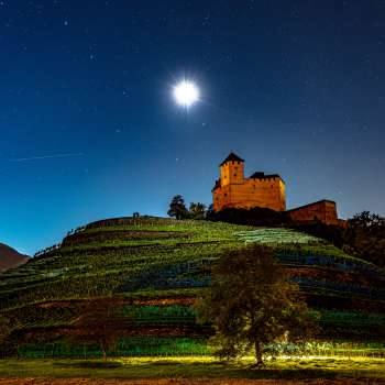 Le château illuminé de Gutenberg la nuit sous la pleine lune, niché dans les vignobles