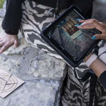 Une joueuse utilise son iPad pour résoudre une énigme dans une salle d'aventure en plein air
