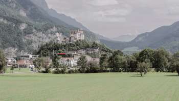 Vue majestueuse sur le château de Gutenberg à Balzers, entouré de champs verdoyants et des impressionnantes Alpes.