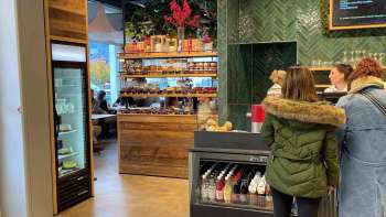 Des clientes à la caisse, entourées d'une décoration en bois accueillante et de produits frais