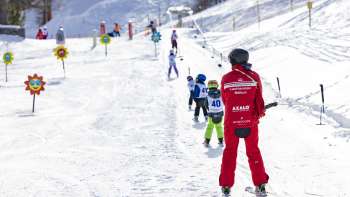 Un moniteur de ski et des enfants sur le télésiège du parc Malbi