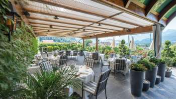 Elégante terrasse de restaurant avec des tables couvertes et une vue panoramique sur les Alpes liechtensteinoises.