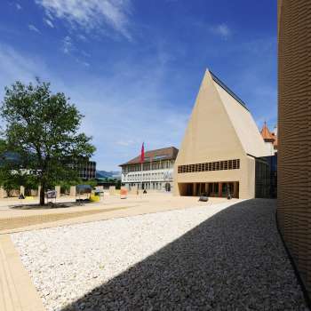 Vue sur la place Peter Kaiser au pavage clair, devant le bâtiment du Landtag à Vaduz, avec son ensemble architectural moderne.