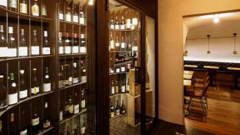 Armoire à vin moderne avec des bouteilles raffinées dans le WY Weinbar stylé WY Weinbar, vue sur la salle de dégustation adjacente.