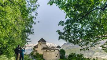 Depuis le sentier de promenade, deux personnes admirent la vue sur le château de Vaduz
