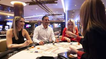 Ambiance conviviale à la table de jeu : trois clients s'entretiennent avec la croupière du casino Schaanwald, aménagé avec goût.
